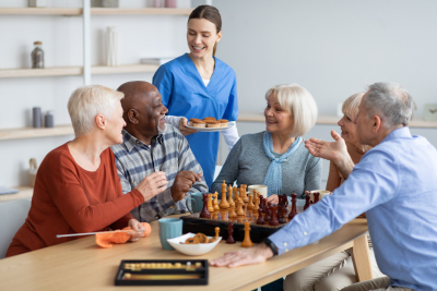 nurse holding plate with cupcakes, talking to elderly people